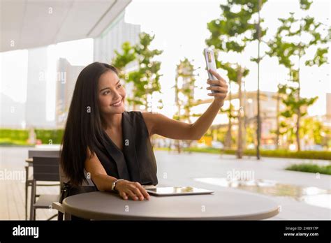 Portrait Of Beautiful Asian Woman Sitting Outdoors At Coffee Shop Restaurant During Summer Stock