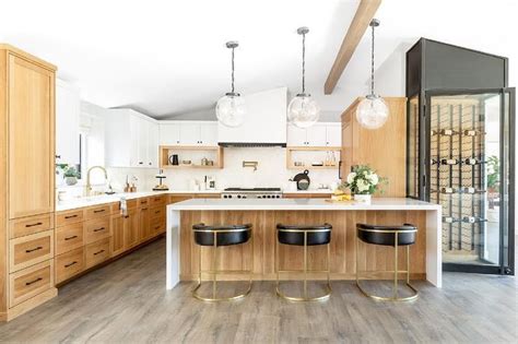 A great and easy way to update the 80's oak cabinets themselves is to update your hardware! Glass globe lanterns decorate a golden oak kitchen island with a white quartz waterfall cou ...