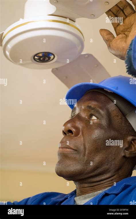 african american construction worker handyman carpenter electrician fixing ceiling fan stock