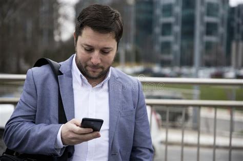 Businessman Using Smartphone Outdoors In Front Of Office Building