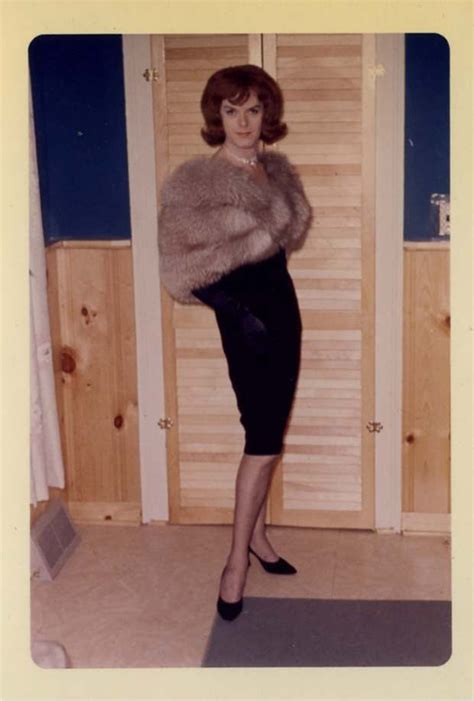 An Old Photo Of A Woman Standing In Front Of A Door Wearing A Fur Coat