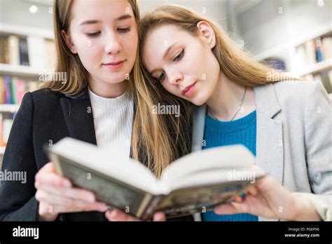 Portrait Of Two Teenage Girls Reading Booktogether In A Public Library