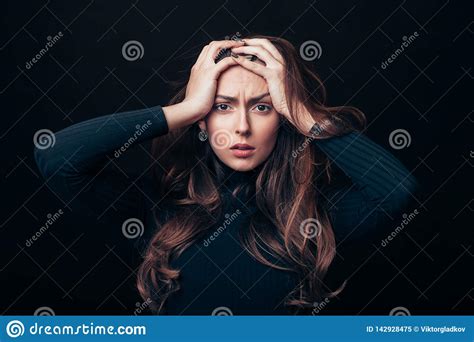 upset offended beautiful woman holding her hands on head isolated on black background stock