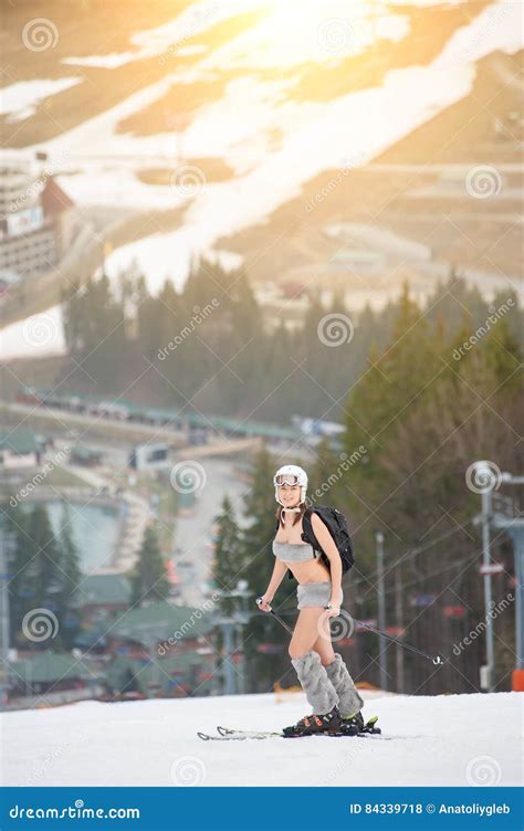 Beautiful Naked Girl Standing On The Snowy Slope Of The Mountain Wearing Helmet Ski And