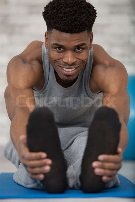Muscular Man Stretching Forward And Holding His Feet Stock Image