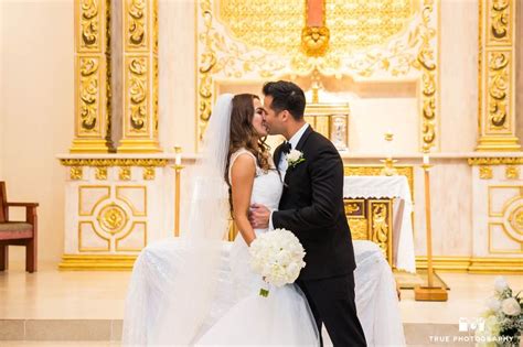 A Bride And Groom Kiss In Front Of The Alter At Their Wedding Ceremony