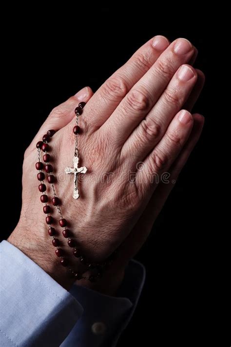 Male Hands Praying Holding A Rosary With Jesus Christ In The Cross Or