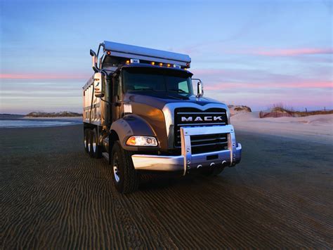A Mack Truck Parked On The Beach At Sunset