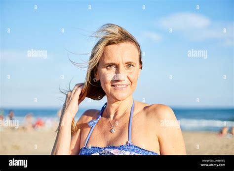 portrait of a beautiful smiling middle aged woman on the beach the sky is clear and there is