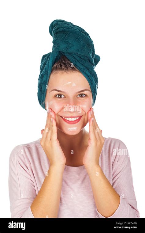 Young Woman Applying Face Moisturizer After Shower Wearing A Towel On Head Isolated