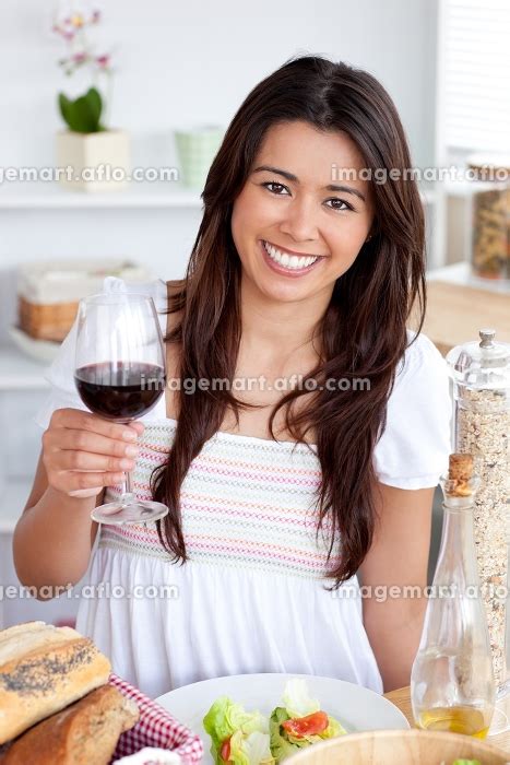 Goodlooking Woman Sitting On Sofa And Drinking A Glass Of Red Wineの写真素材 [31434790] イメージマート