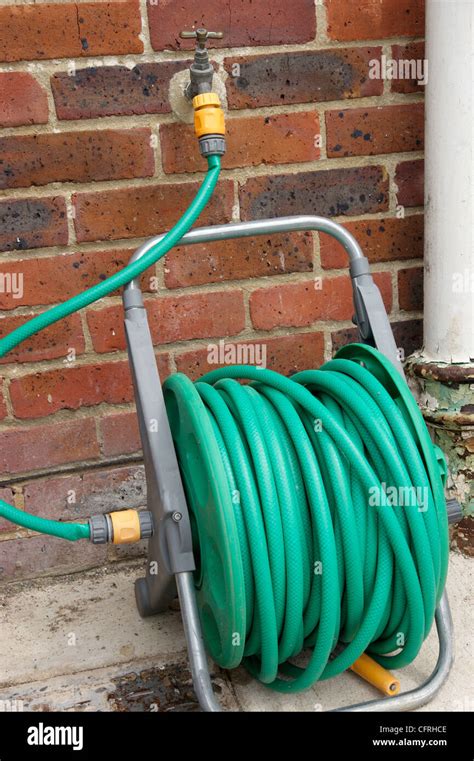 Hose Pipe On Reel Attached To Outside Tap In Garden With The Hosepipe