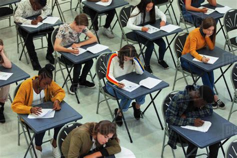 Focused High School Students Taking Exam At Desks In Classroom Stock