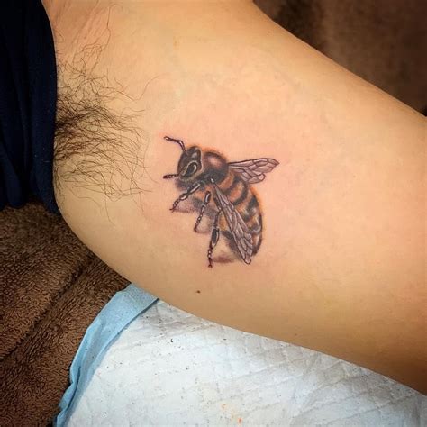 A Small Tattoo Of A Bee On The Back Of A Womans Left Arm