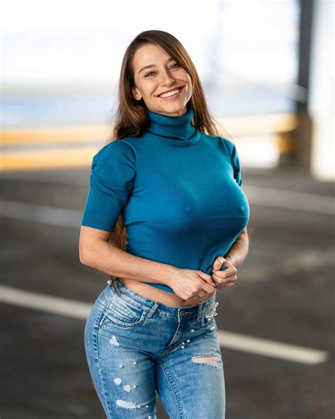 A Woman In Blue Shirt And Jeans Posing For The Camera With Her Hands On Her Hips