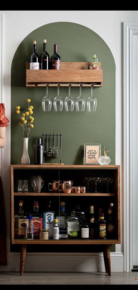 A Bar With Wine Glasses And Liquor Bottles On The Top Shelf Next To A
