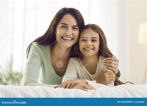 Portrait Of Happy Mother And Little Daughter Cuddling On Bed And Smiling At Camera Stock Image