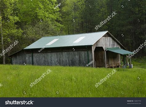 Side View Of A Weathered Old Pole Barn With Green Roof In A Pasture