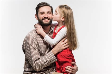 Niña Abrazando A Su Padre Sobre Una Pared Blanca Foto Gratis
