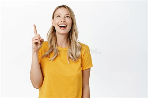 Excited Smiling Blond Girl Looking And Pointing Up With Amused Face