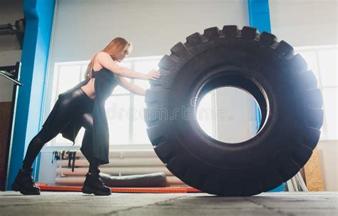 Fit Female Athlete Working Out With A Huge Tire Turning And Carry In