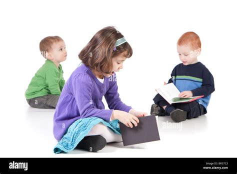 Three Kids Sitting On Floor And Reading Books Isolated On White With