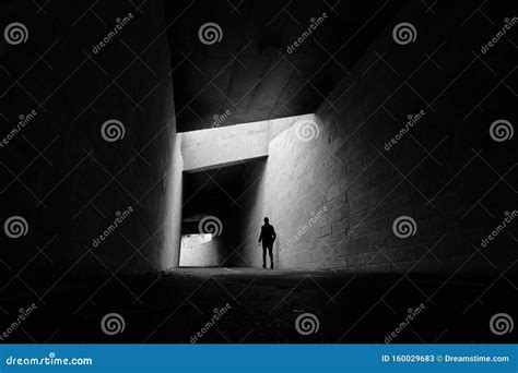 Black And White Scene Of Lone Man Walking Through Tunnel Stock Image