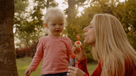 Mother And Daughter Blowing Bubbles In Park Stock Video Footage 0012