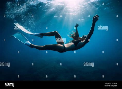 Free Diver Woman With White Fins Glides Underwater With Amazing Sun