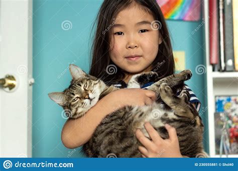 Child Portrait With Domestic Pet Cute Asian Girl Holding Tabby Cat