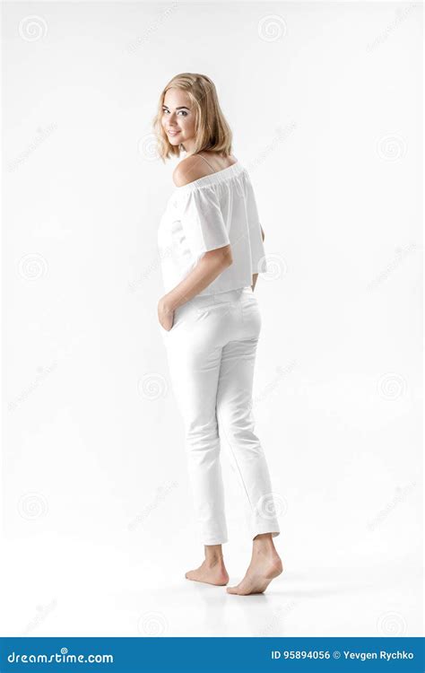 Schöne Lächelnde Blonde Frau In Der Weißen Bluse Und In Den Hosen Auf Weißem Hintergrund