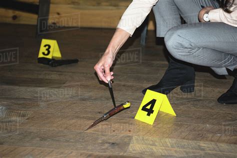 Cropped View Of Female Hand Examining Knife Near Evidence Markers At