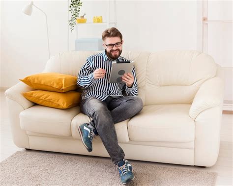 Hombre Relajante En Casa En El Sofá Con Tableta Foto Gratis