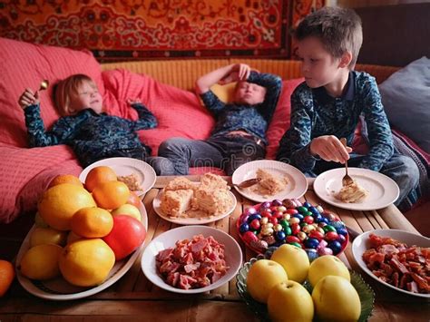 Three Funny Children Sit On Sofa In Front Of Festive Table Celebrate
