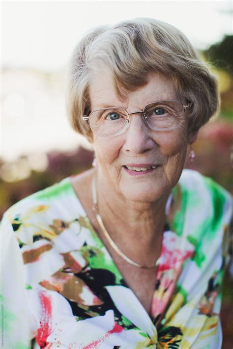 Happy Portrait Of Elderly Woman Outside Near Flowers By Stocksy