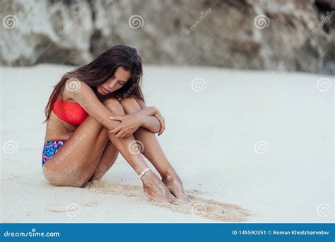 Slender Tanned Woman In Colored Swimsuit Posing On Beach With White