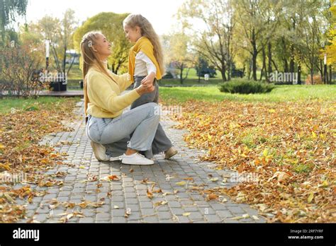 Young Blonde Mother Kneeling And Hugging The Girl Daughter In The Park