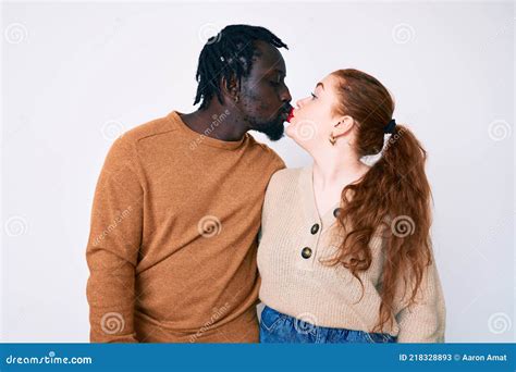 Interracial Couple Wearing Casual Clothes Looking At The Camera Blowing A Kiss On Air Being