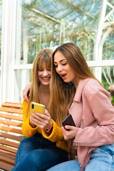 Two Young Girls Smile While Using A Cell Phone Stock Image Image Of
