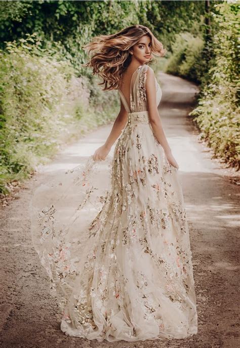 A Woman In A Long Dress Is Walking Down The Road With Her Hair Blowing In The Wind