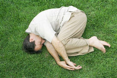 Man Lying In Fetal Position On Grass Eyes Closed High Angle View