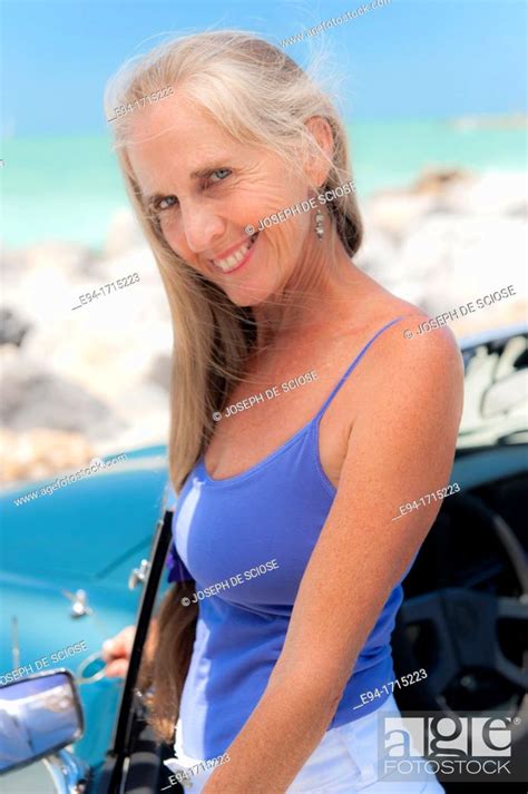 Portrait Of A 57 Year Old Woman Standing By Her Mg Car At A Beach