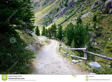 Rocky Trail Leading To Valley Surrounded By Forests And High Mountains