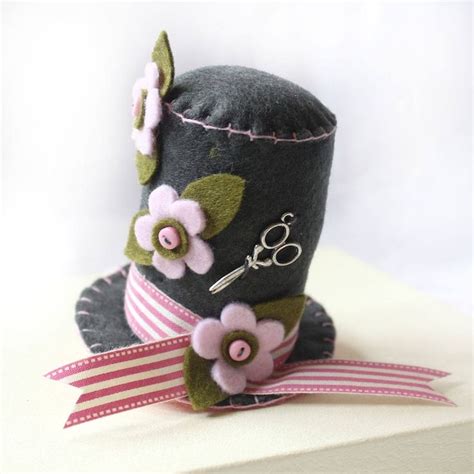 A Gray Hat With Pink Flowers And Scissors On The Top Is Sitting On A