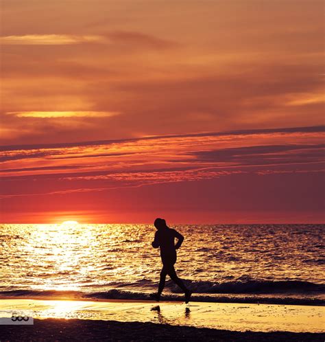 Woman Running At Beautiful Sunset On The Beach By Maciej Bledowski On