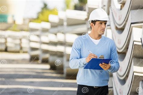 Male Supervisor With Clipboard Inspecting Stock At Site Stock Image