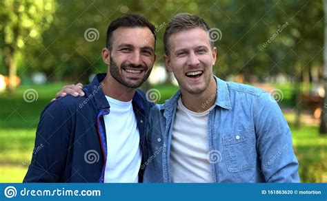 Best Male Friends Hugging Smiling On Camera Outdoors