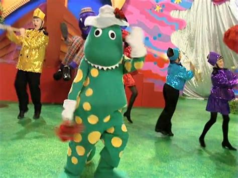 A Group Of People Dressed In Costumes Dancing On A Green Floor With