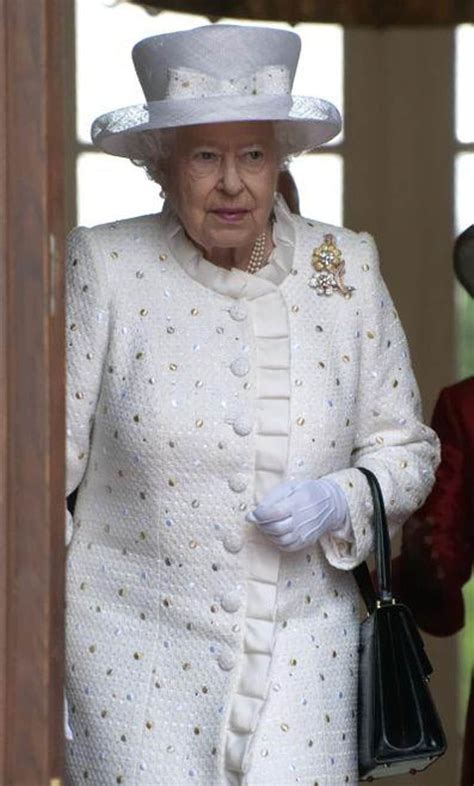 an older woman wearing a white suit and hat walking next to another