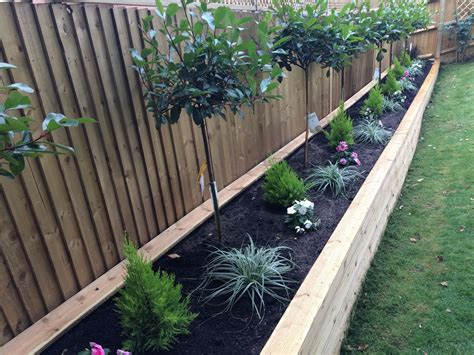 There are a number of ideas for upcycling older items into garden fence décor. A raised wooden flower bed with red robin trees, conifers ...